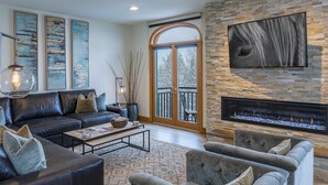 A modern living room with a fireplace, leather sofas, and artwork on the walls.