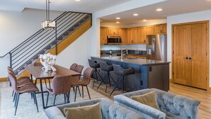 A modern kitchen with stainless steel appliances, a wooden island, and a dining area with a table and chairs.