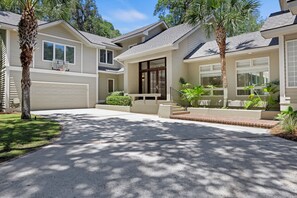 Una casa residencial con entrada para vehículos, garaje y porche delantero con escalones.