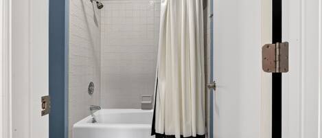 Un baño con bañera, inodoro y cortina de ducha.