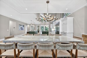 Un comedor moderno con una mesa de vidrio, sillas tejidas y una lámpara colgante original.
