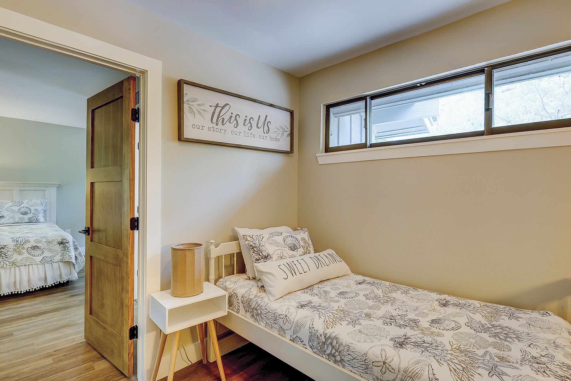 A bedroom with a bed, a bedside table, a window, and a door.