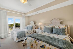 Ein Schlafzimmer mit zwei Betten, einem Balkon und Blick auf Grünflächen.