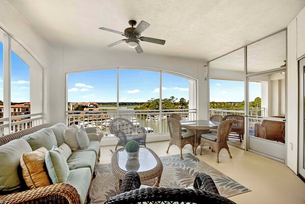 Ein geräumiger Balkon mit Deckenventilator, eine Sitzecke mit Sofa und Sesseln sowie Blick auf den Hafen.