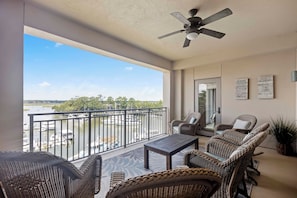 A balcony with wicker furniture, a ceiling fan, and a view of a marina. - Spectacular Harbourfront Villa completely renovated located in Shelter Cove (Hilton Head)