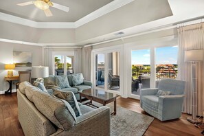 A spacious living room with a sofa set, a coffee table, and a chair. There is a large window with a view of a residential area. - Spectacular Harbourfront Villa completely renovated located in Shelter Cove (Hilton Head)