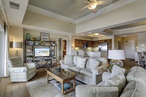 Ein geräumiges Wohnzimmer mit einer Sofagarnitur, einem Couchtisch und einem Fernseher, der 'Island Getaway Rentals' anzeigt.