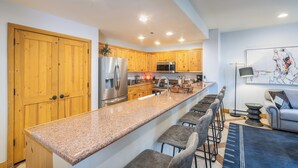 A modern kitchen with wooden cabinets, stainless steel appliances, and a granite countertop. - 3-Bedroom Private Mountainside Condo (Mountain Village)