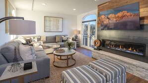 A modern living room with a fireplace, a large TV, and a comfortable seating area. - Mountain Modern Luxurious 4-Bedroom Retreat With the Best Views At Bear Creek (Mountain Village)