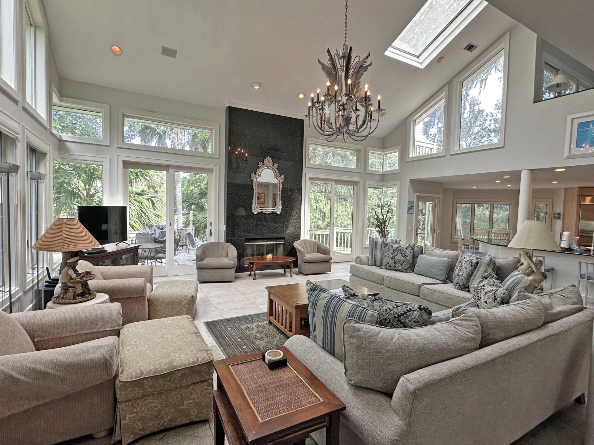 A spacious living room with a fireplace, comfortable seating, and large windows.