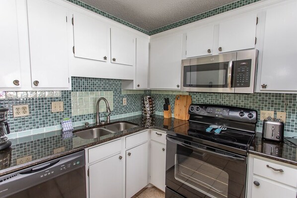 A kitchen with white cabinets, a microwave, a stove, and a dishwasher.
