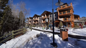 A multi-story building with balconies, a clock, and a snow-covered ground. - AC! On River Trail. Walk to Dining, Shops, Events, Theater, Weddings (Silverthorne)