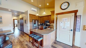 A modern kitchen with wooden cabinets, stainless steel appliances, and a central island with bar stools. - AC! On River Trail. Walk to Dining, Shops, Events, Theater, Weddings (Silverthorne)