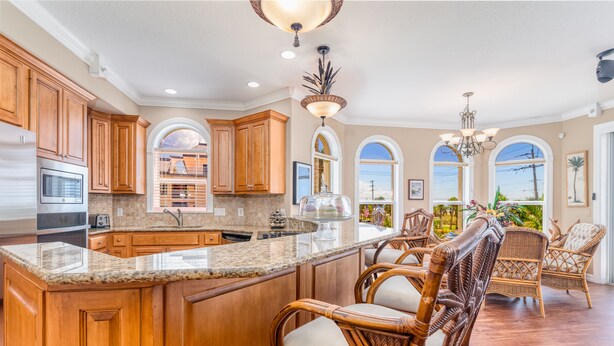 A spacious kitchen with wooden cabinets, a granite countertop, and a large island with bar stools. - 🌴 Villa Vista Mare | Gulf Views, Semi-Private Pool + Steps to Siesta Beach (Siesta Key)