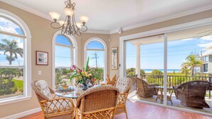 A spacious room with a large dining table surrounded by wicker chairs, a chandelier, and large windows offering a view of the ocean. - 🌴 Villa Vista Mare | Gulf Views, Semi-Private Pool + Steps to Siesta Beach (Siesta Key)
