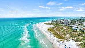 A coastal beach with a sandy shore, a few umbrellas, and buildings in the background. - 🌴 Villa Vista Mare | Gulf Views, Semi-Private Pool + Steps to Siesta Beach (Siesta Key)