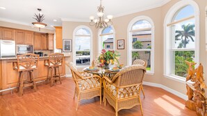 A spacious kitchen with wooden cabinets, a stainless steel refrigerator, and a dining area with wicker chairs and a glass table. - 🌴 Villa Vista Mare | Gulf Views, Semi-Private Pool + Steps to Siesta Beach (Siesta Key)