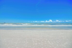Une plage avec un ciel dégagé et une mer calme.