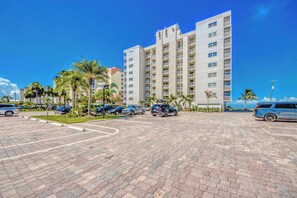 A multi-story parking structure with a paved ground, surrounded by palm trees and a clear blue sky.