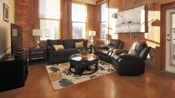 Olohuone, jossa on tiiliseinä, takka, sohva, sohvapöytä ja televisio.