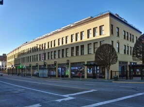 A multi-story building with a flat facade, large windows, and a row of storefronts on the ground floor. - Historic Loft w/ Exposed Brick & Timber Beams (Victoria, B.C.)