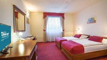 A hotel room with two beds, a desk with a telephone, and a mirror.