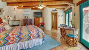 A bedroom with a large bed, a ceiling fan, a television, and a dining area with wicker furniture. - 6 Mi to Texas Tech: Studio w/ Shared Pool & Grill (Lubbock)