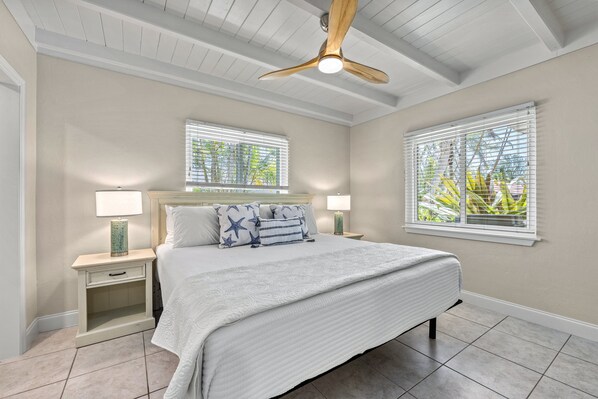 A bedroom with a bed, two nightstands, a ceiling fan, and two windows with blinds. - 🌴 Crescent Cottage | Private Pool, Pet Friendly, Walk to Crescent Beach (Siesta Key)