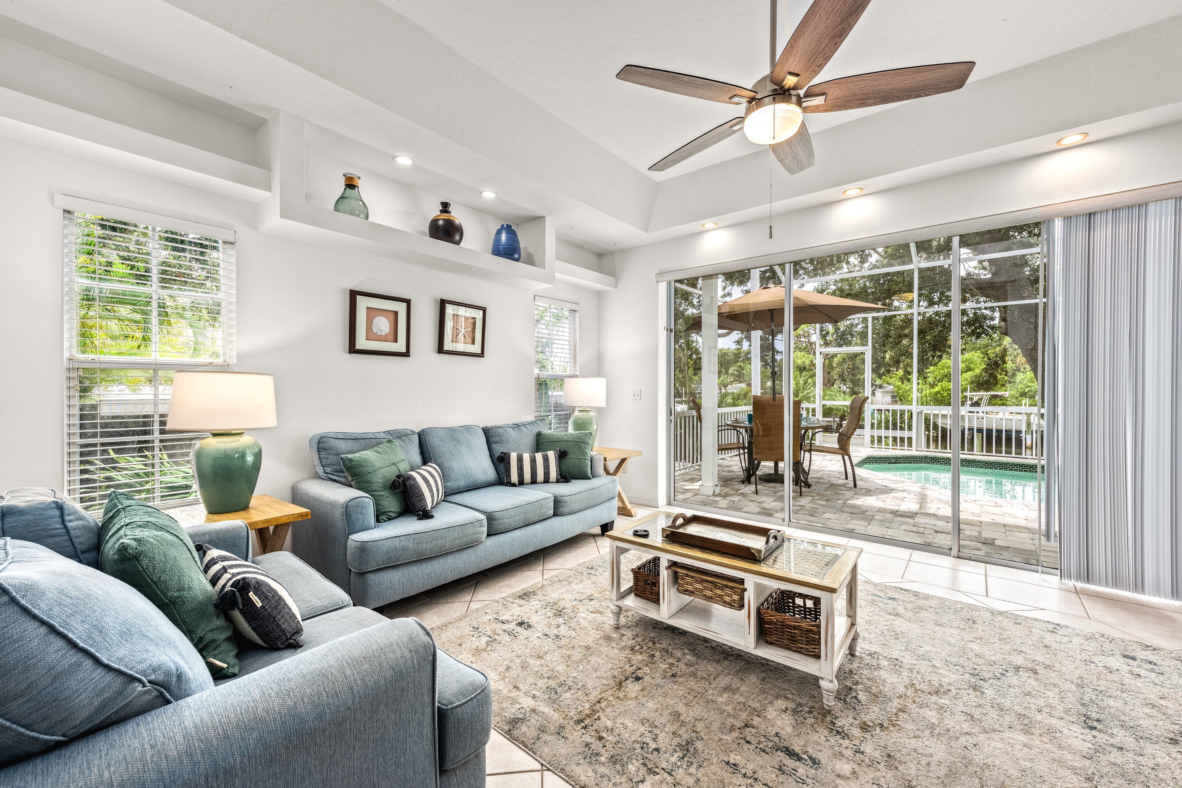 A spacious living room with a blue sofa, a coffee table, and a ceiling fan.