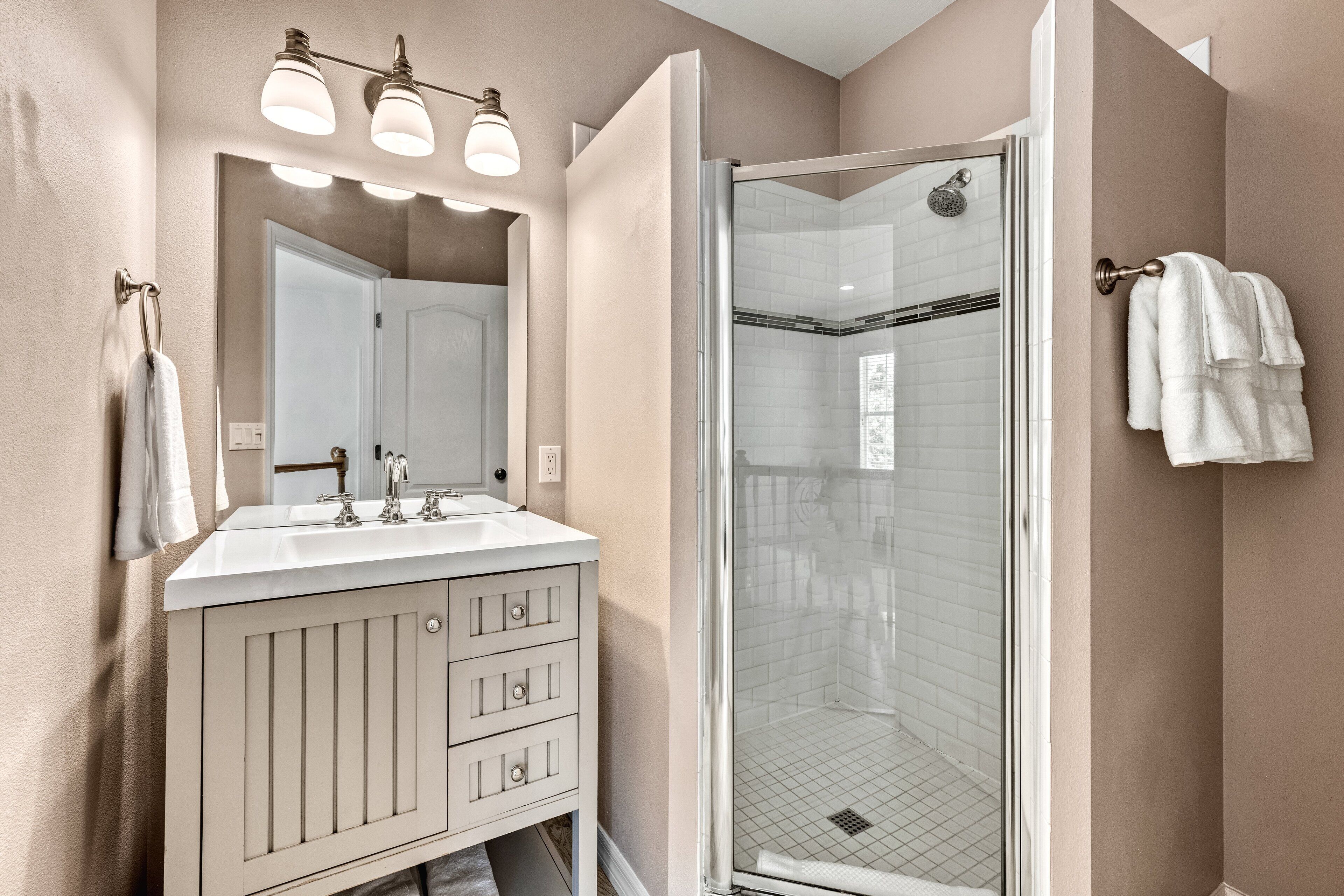 A bathroom with a double sink vanity, a glass-enclosed shower, and a towel rack.