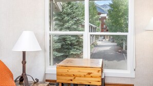 A room with a large window, a wooden table, and a lamp. - Updated Hotel Room With Kitchenette at the Mountainside Inn (Telluride)
