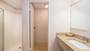 A bathroom with a granite countertop, a sink, and a mirror. - Upgraded Floors and King Bed at Mountainside Inn (Telluride)