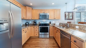 Una cucina moderna con mobili in legno, elettrodomestici in acciaio inossidabile, piani di lavoro in granito e un'ampia finestra che offre luce naturale.