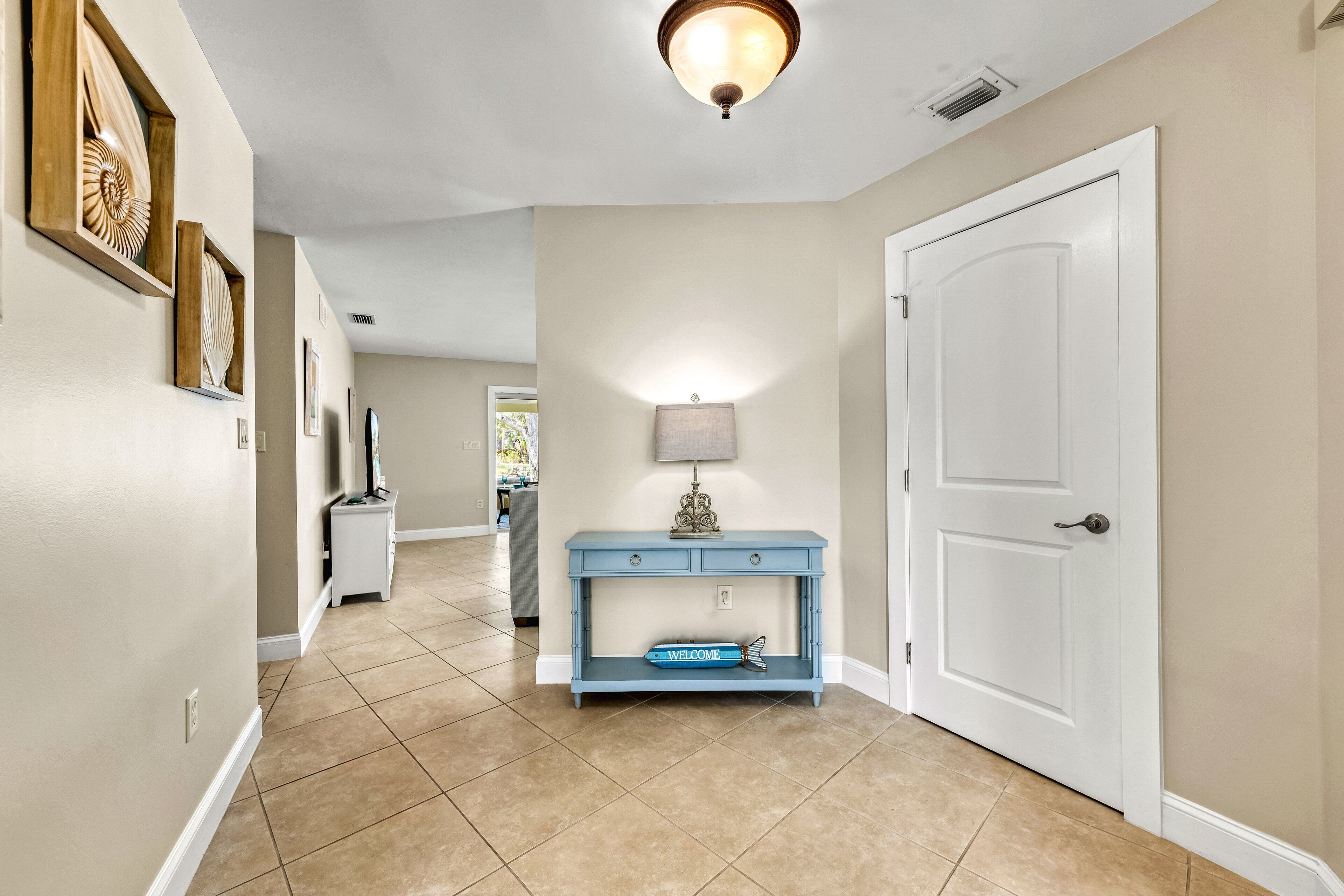 A hallway with a blue console table, a white door, and a ceiling light fixture.