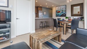 Een moderne woonkamer met een houten salontafel, een zwarte leren bank en een televisie.