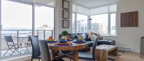 Ein modernes Wohnzimmer mit Essbereich, großen Fenstern und Blick auf die Stadt.