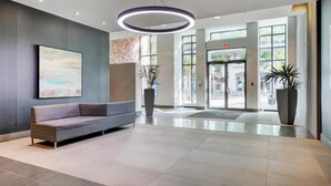 Een moderne lobby met een bank, grote ramen en een ronde lamp.