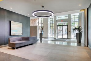 A modern lobby with a sofa, large windows, and a circular light fixture. - Bright Open-Concept Sanctuary at The Era (Victoria)