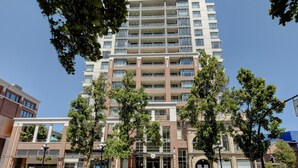Een meerlaags gebouw met een centrale ingang, omringd door bomen en andere gebouwen.