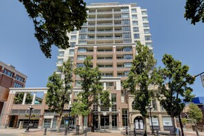 A multi-story building with a central entrance, surrounded by trees and other buildings. - Bright Open-Concept Sanctuary at The Era (Victoria)