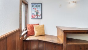 Un coin avec un banc en bois, une affiche au mur et une fenêtre donnant sur un paysage.