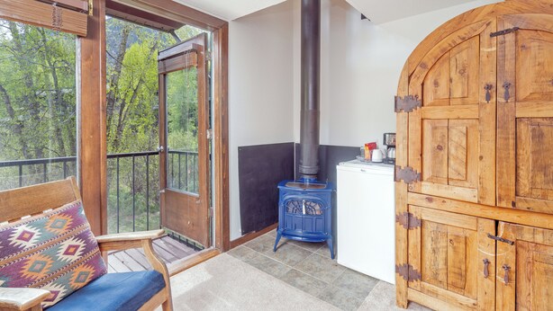 Une pièce avec un banc en bois, un poêle et une grande armoire.