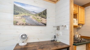 A kitchen with a wooden table, a fan, and a microwave. - Updated, Affordable Pet-Friendly Kitchenette at the Mountainside Inn (Telluride)
