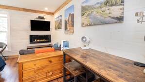 A modern living room with a fireplace, wooden furniture, and wall-mounted artwork. - Updated, Affordable Pet-Friendly Kitchenette at the Mountainside Inn (Telluride)