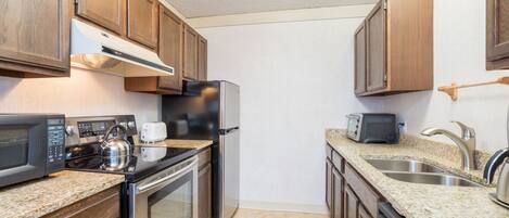 A kitchen with wooden cabinets, stainless steel appliances, granite countertops, and a double sink.