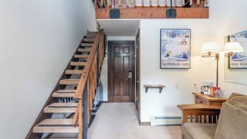 A staircase with wooden steps leading to a door, a sofa, and a lamp on a table.