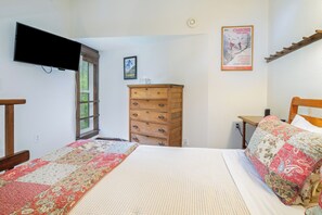 A bedroom with a bed, dresser, and a television mounted on the wall.