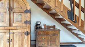 A wooden staircase with a handrail and a wooden cabinet with drawers and a coffee maker.