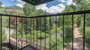 A balcony with a view of a forested area, a river, and distant mountains.