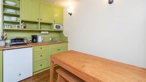 Une cuisine de taille réduite avec des meubles de couleur verte, un four à micro-ondes, un grille-pain et un évier.